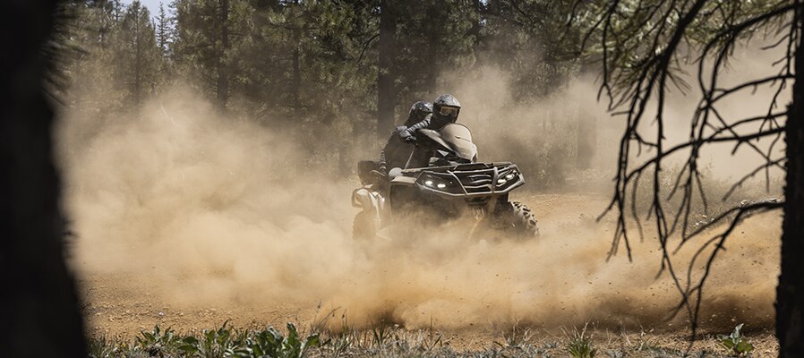 Can-Am Outlander Max raising dust in a forest trail