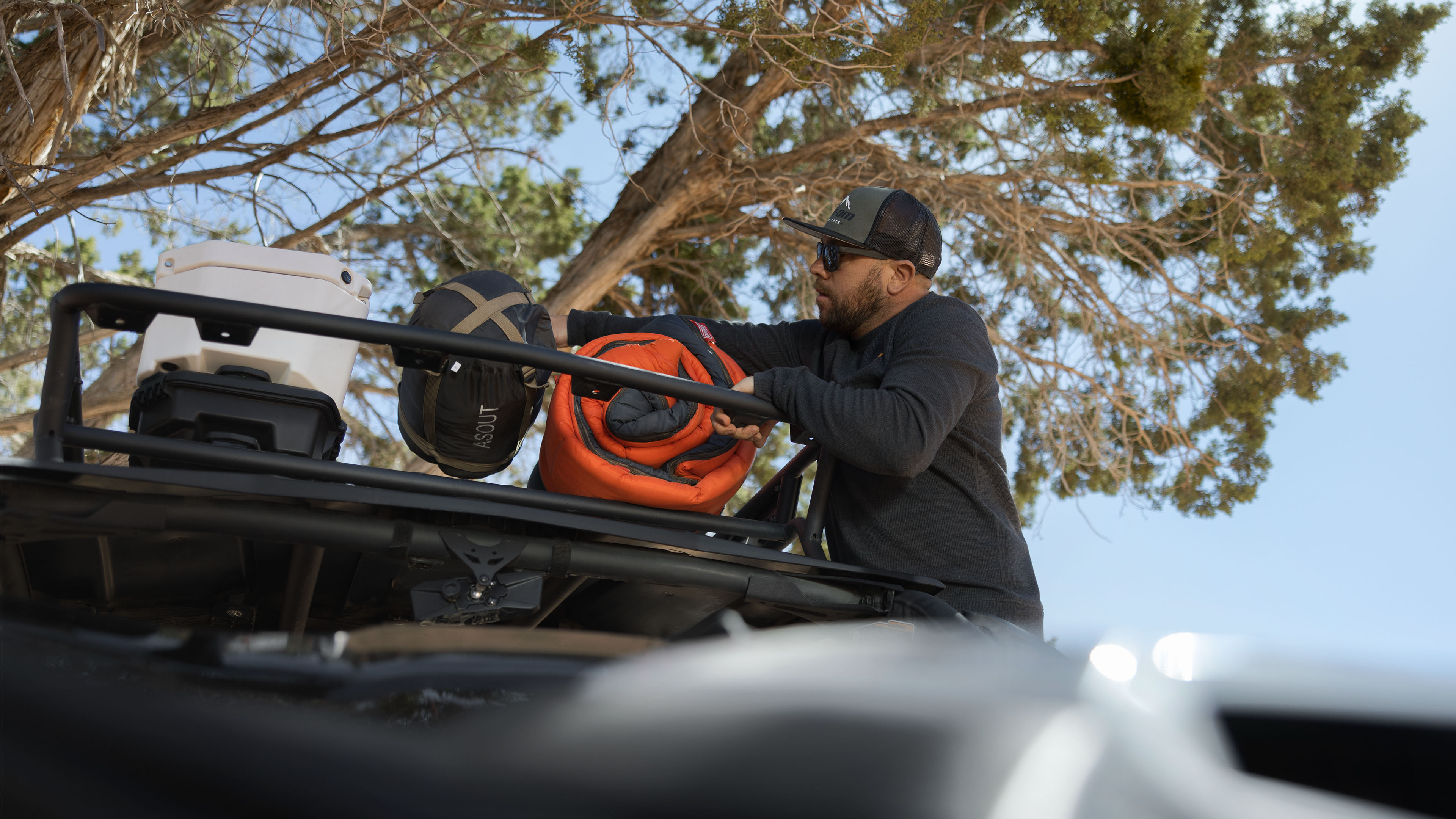 Un amateur de plein air qui place son équipement sur le porte-bagage de toit LinQ de son véhicule Can-Am
