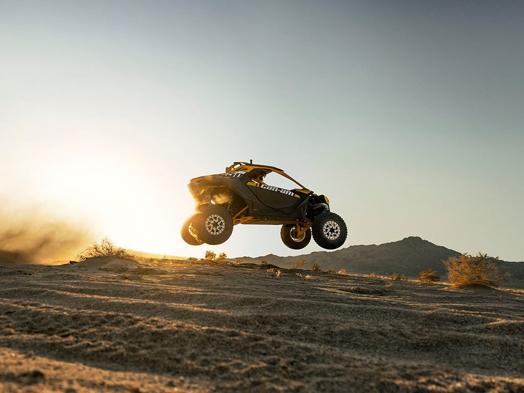 A Can-Am Maverick X3 SxS driving through a sunny desert