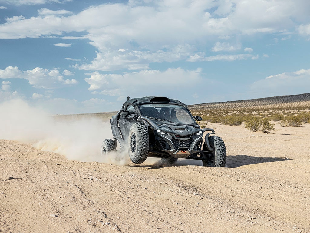 Een bestuurder in een Can-Am Maverick R side-by-side voertuig rijdt in de woestijn