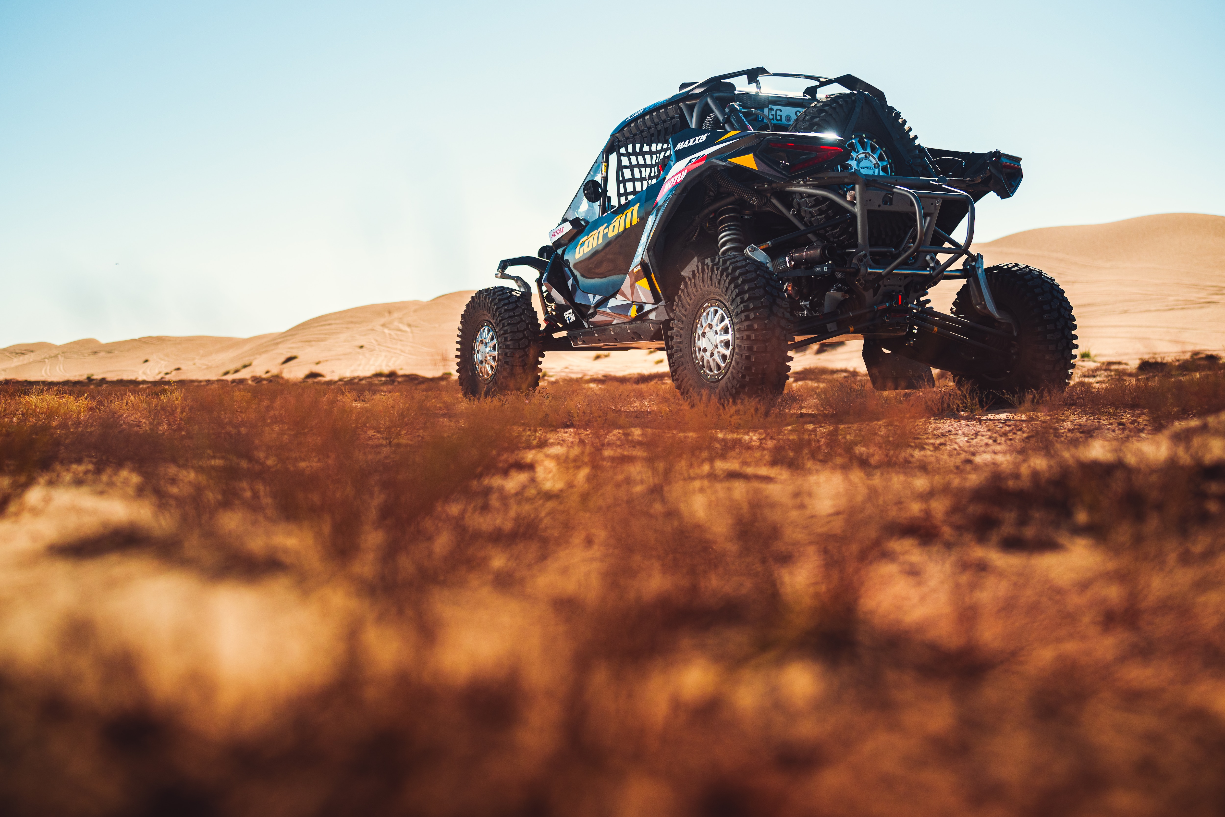 A Can-Am side-by-side rolling down a sand dune 