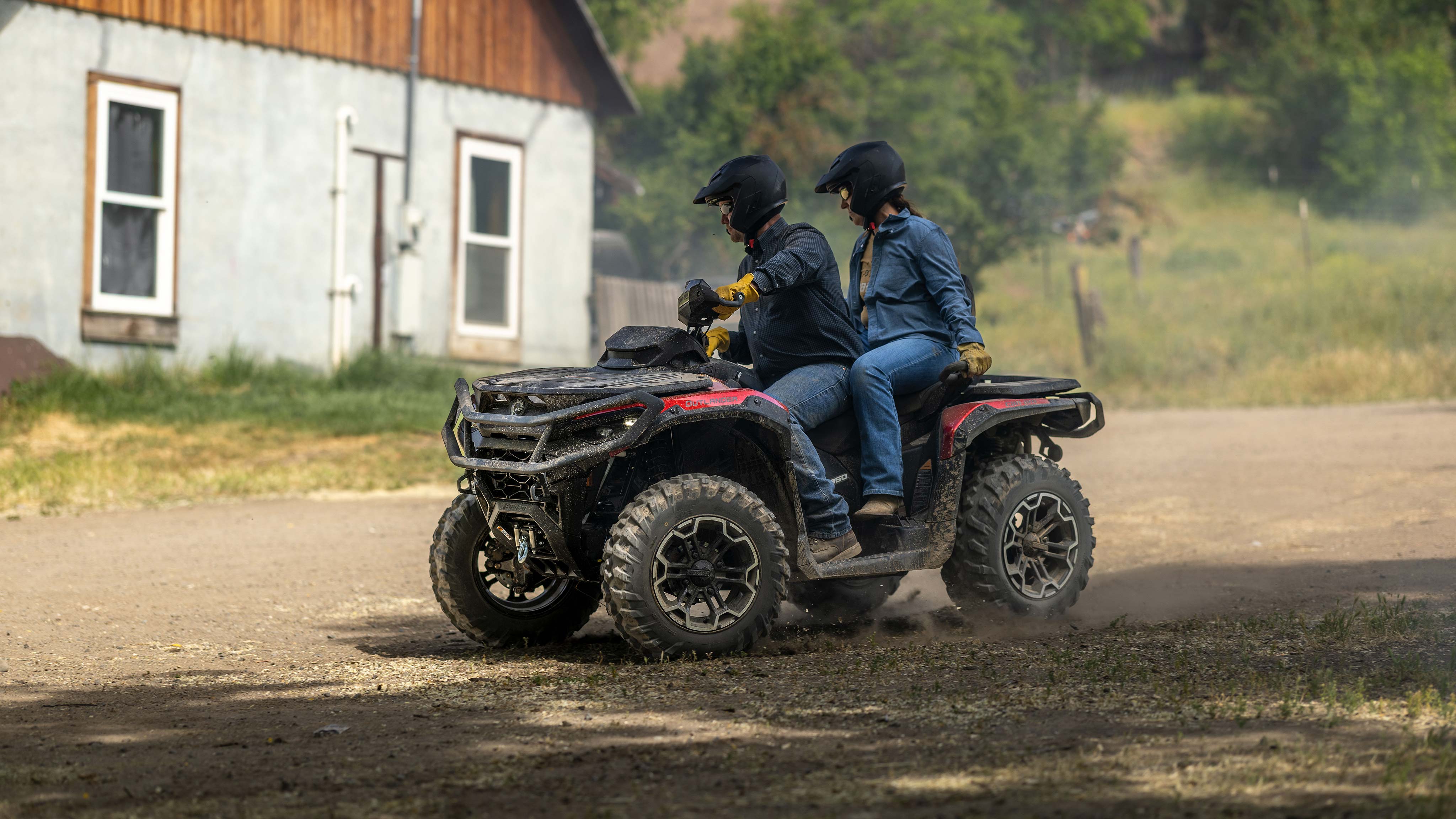 Un homme et une femme sur un Can-Am Outlander Max XT 2025 sur une route non pavée