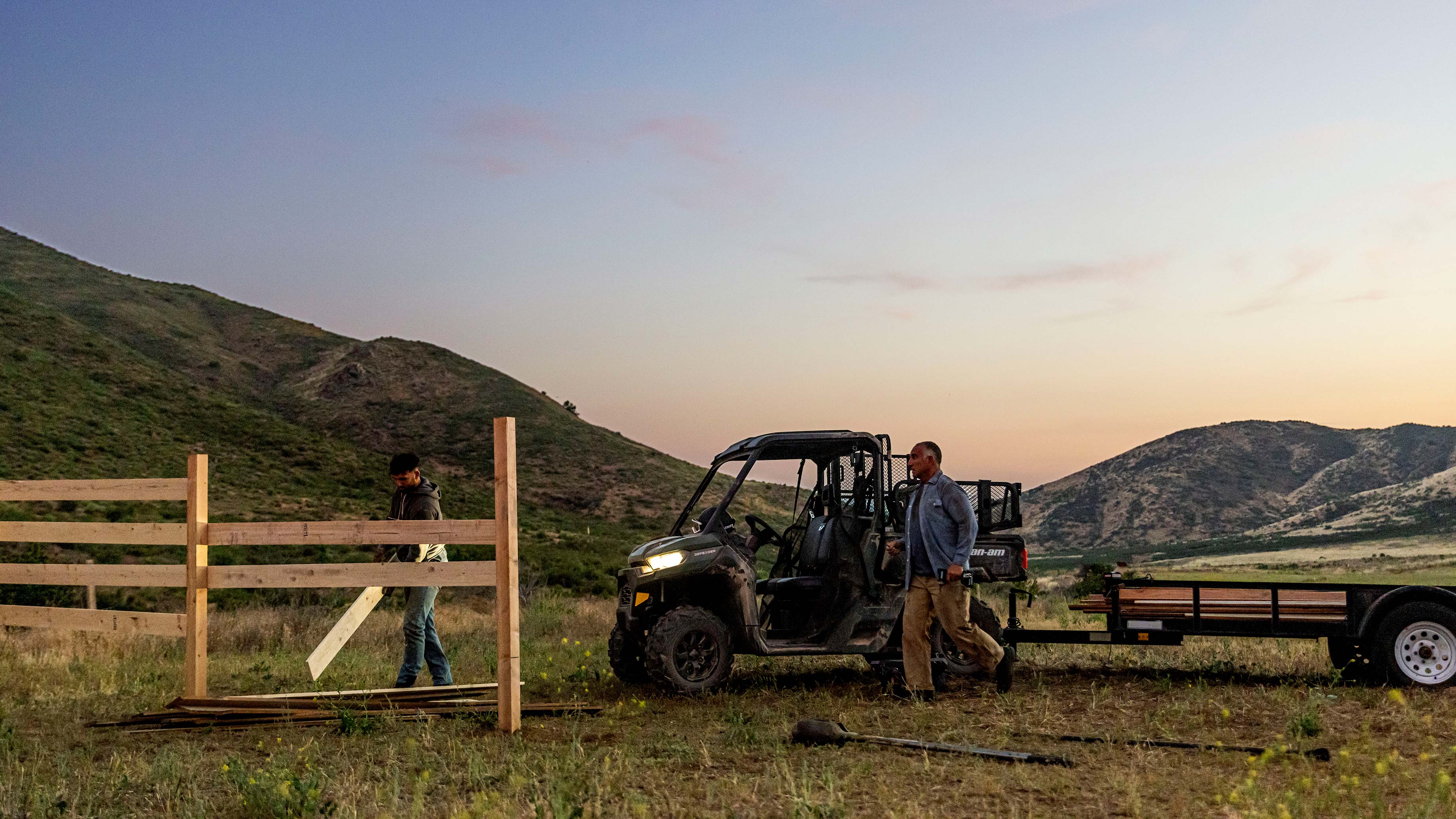 Farmers working with a Can-Am SxS on a fence in a field