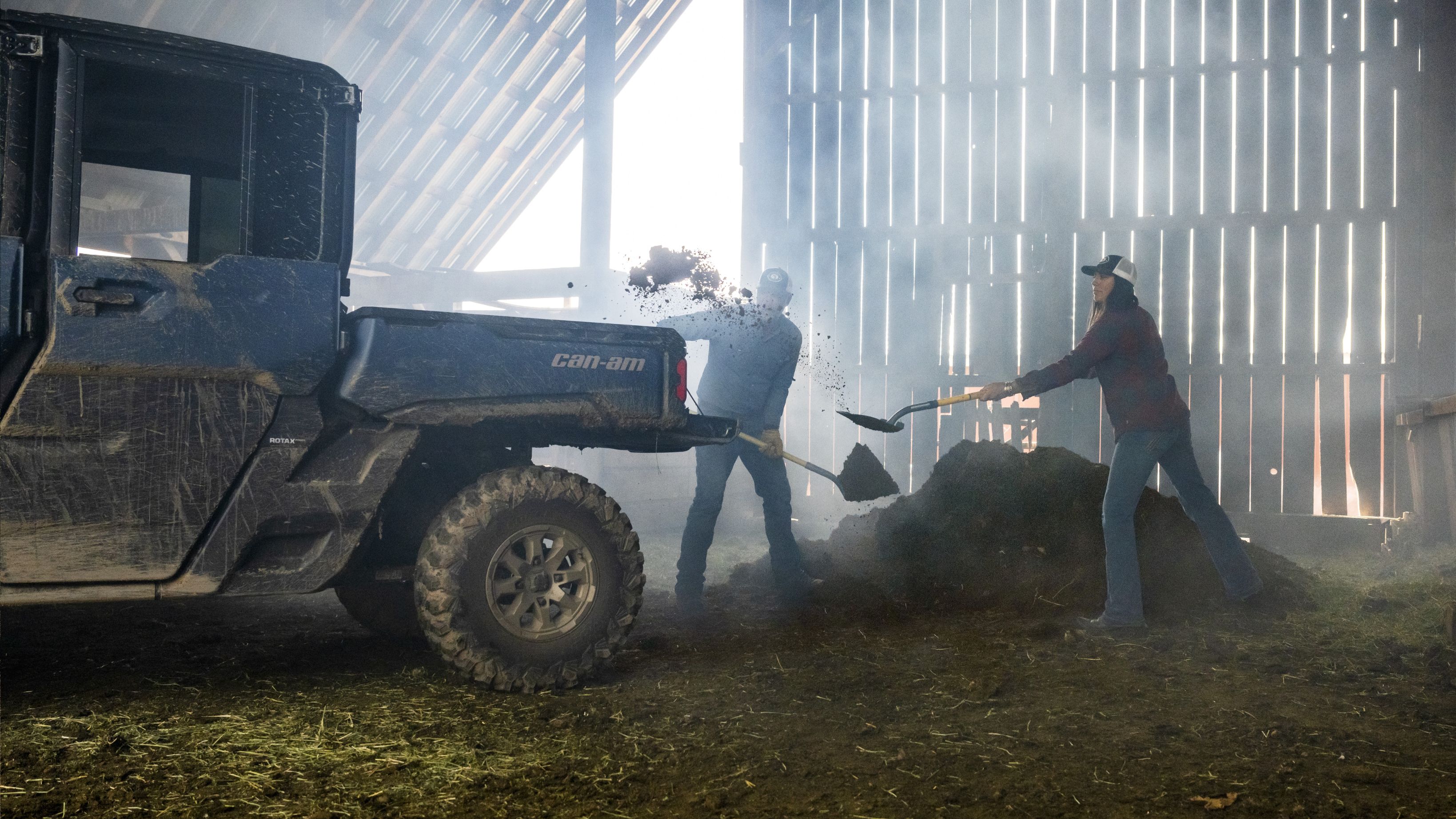 Een man en vrouw storten grond in de laadbak van een Can-Am Traxter Max Limited 2025 SxS