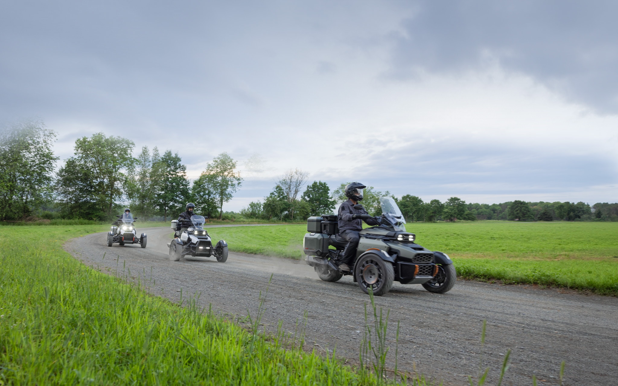 Three Can-Am 3-wheelers following each other on an unpaved road