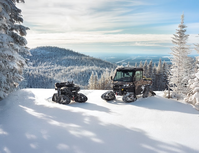 Un Can-Am ATV et un SxS avec des chenilles sur une montagne enneigée
