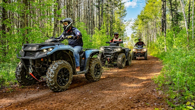 Several Can-Am Outlander ATVs following each other on a trail