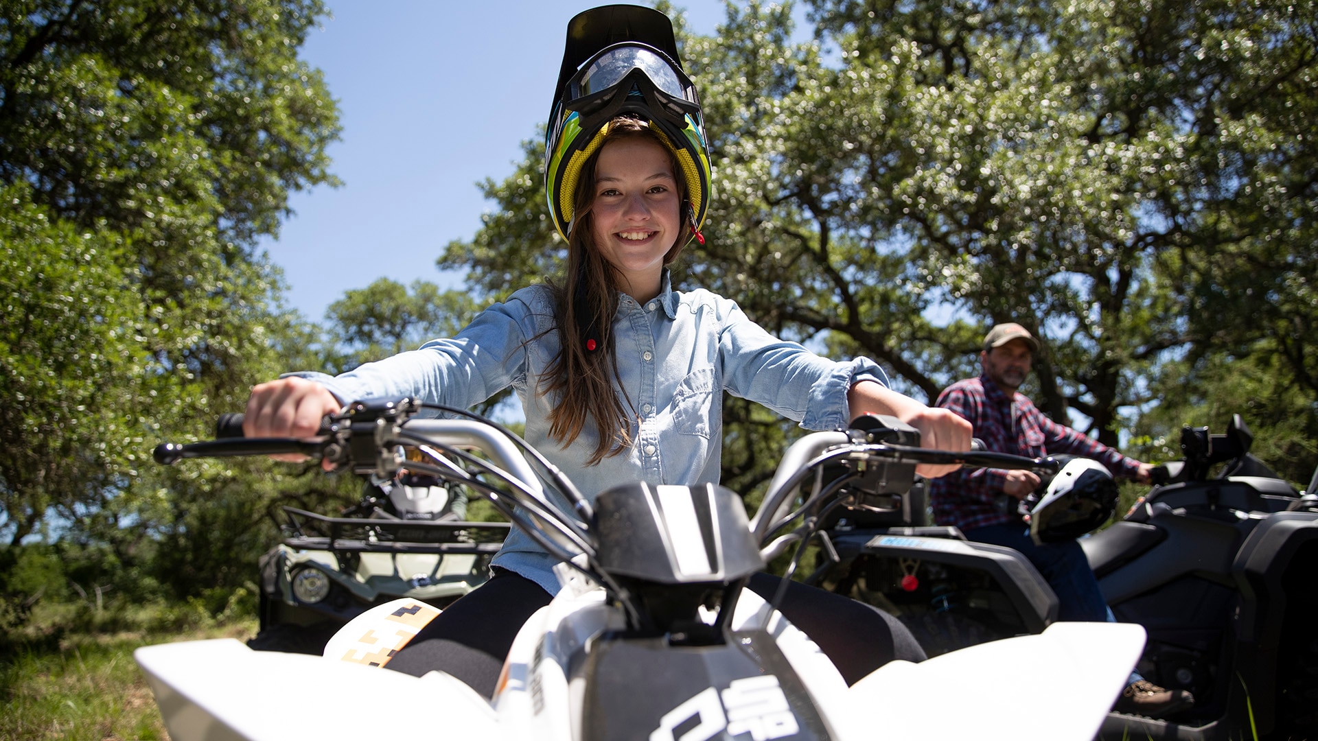 A young girl happy to be riding her Can-Am DS ATV