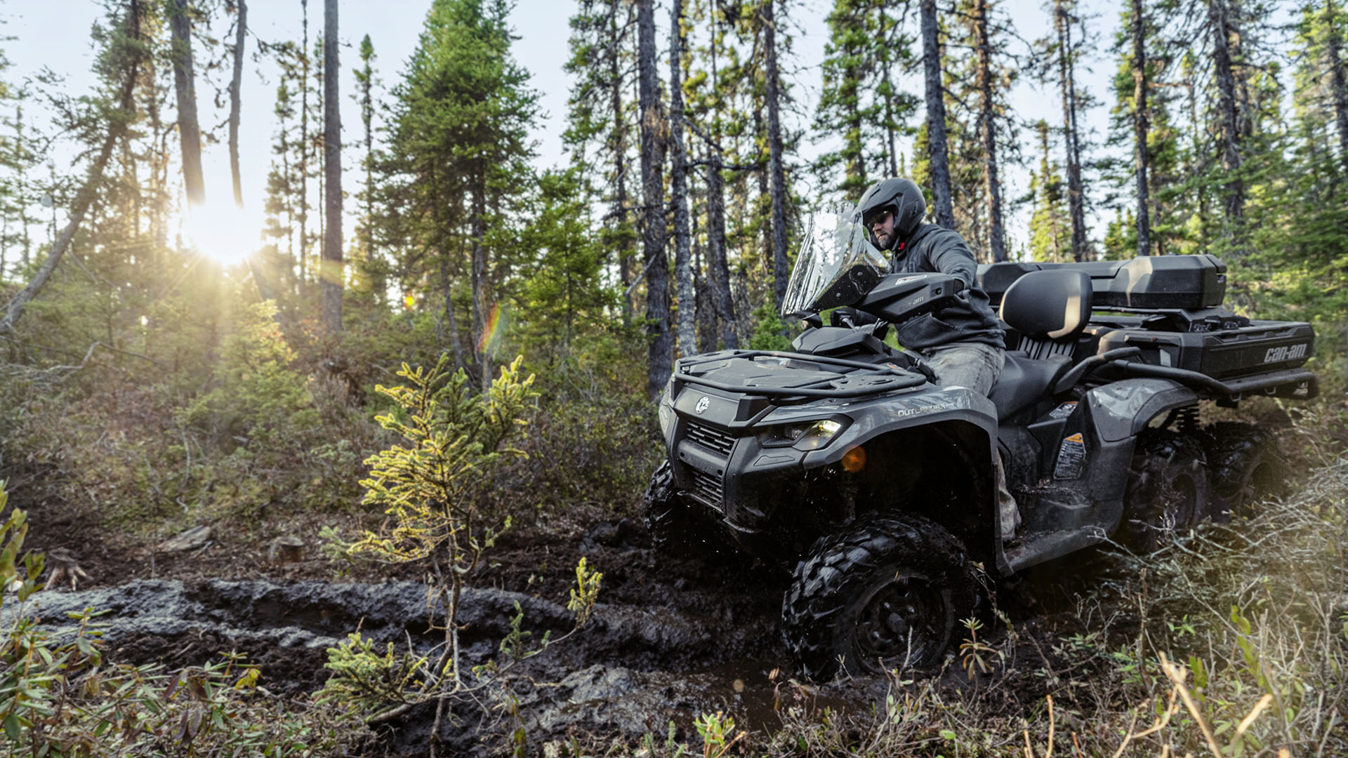 A rider on his 2026 Can-Am Outlander 6x6 driving through the mud in the middle of the forest