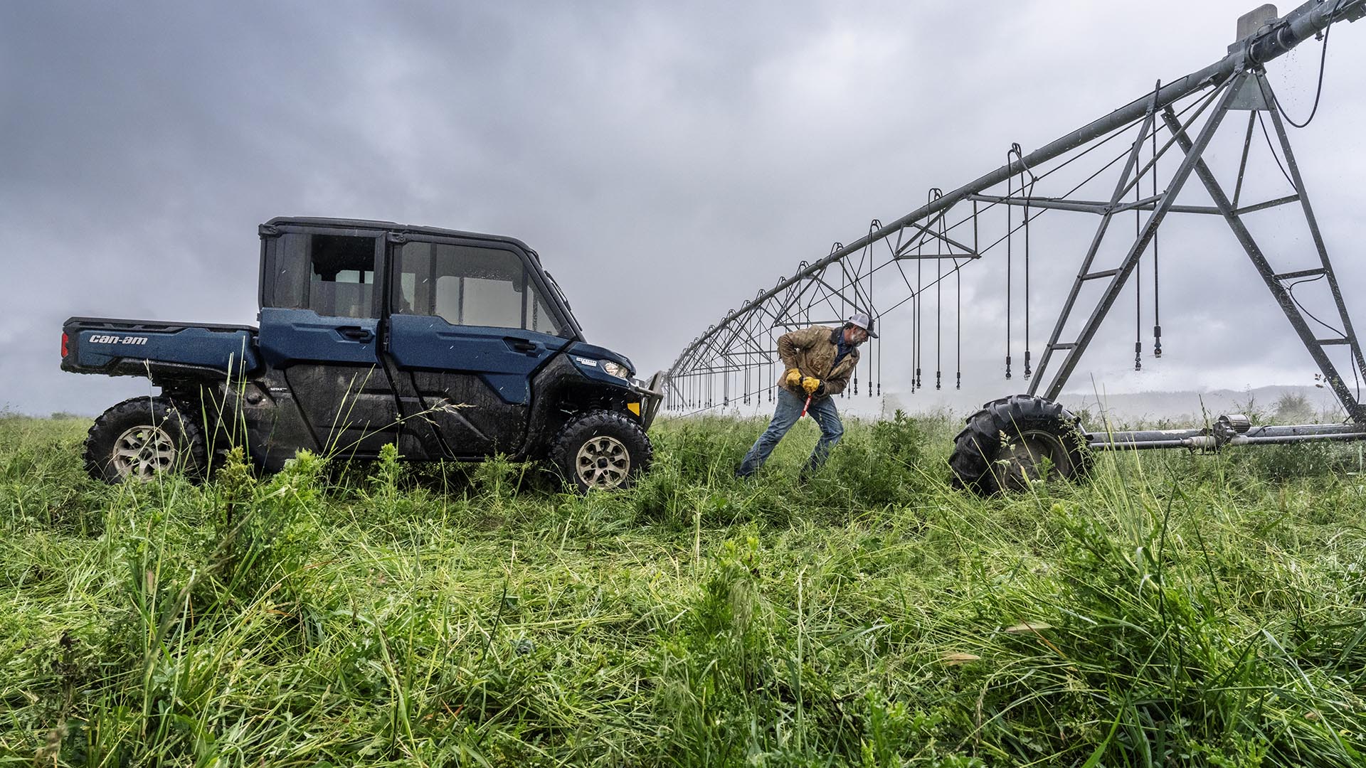 A farmer using the cable connected to his Can-Am Defender side-by-side in the grass
