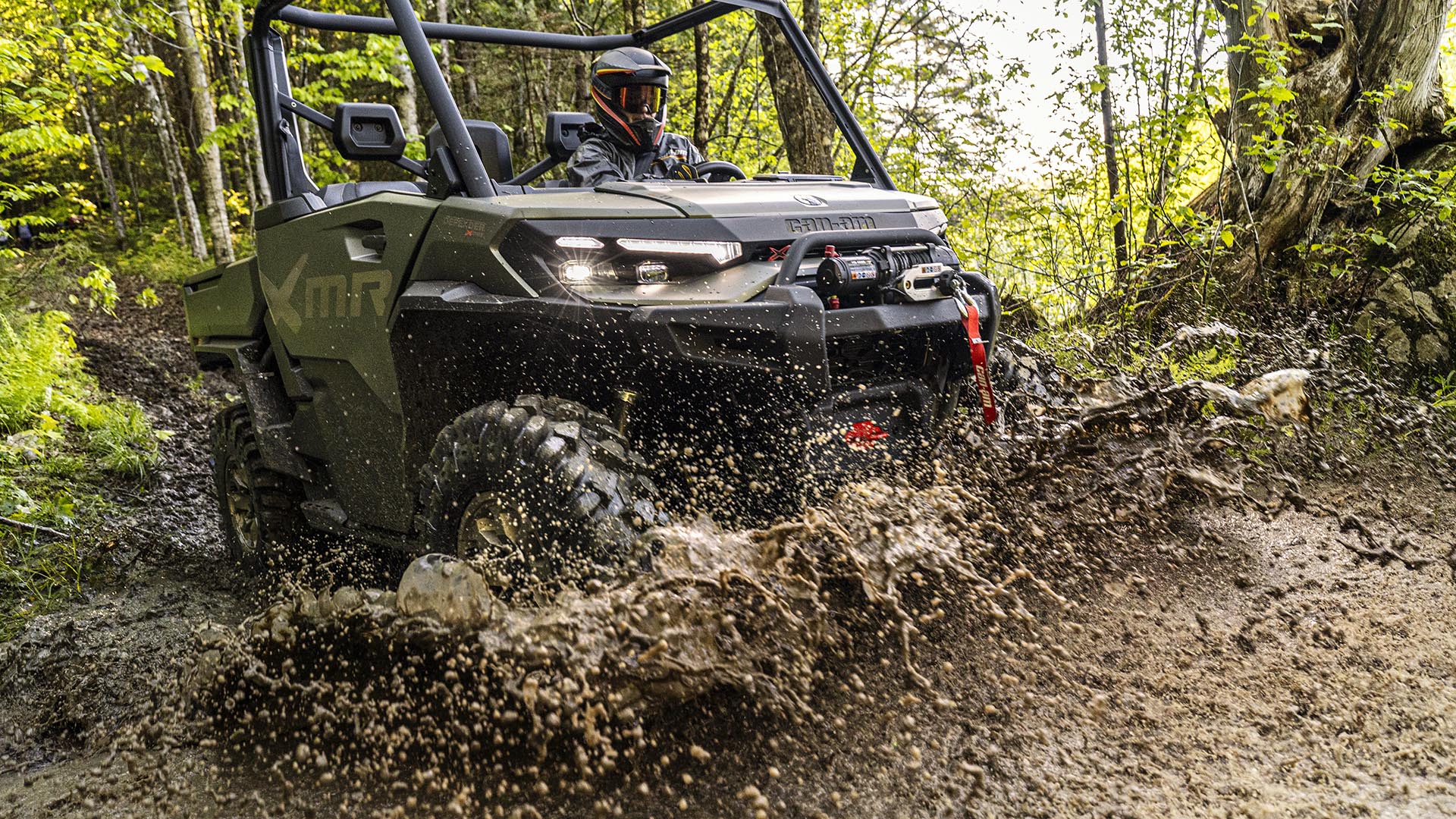 A 2026 Can-Am Defender X MR side-by-side making a splash in the mud