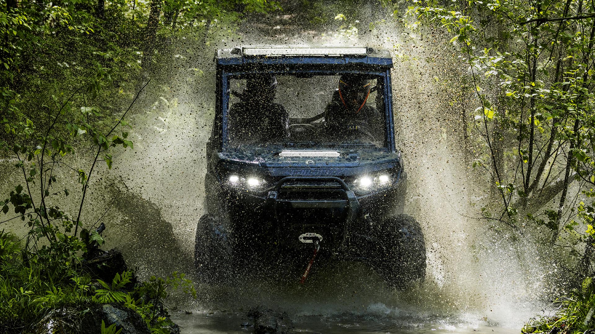 2026 Can-Am Defender SxS riding through a puddle