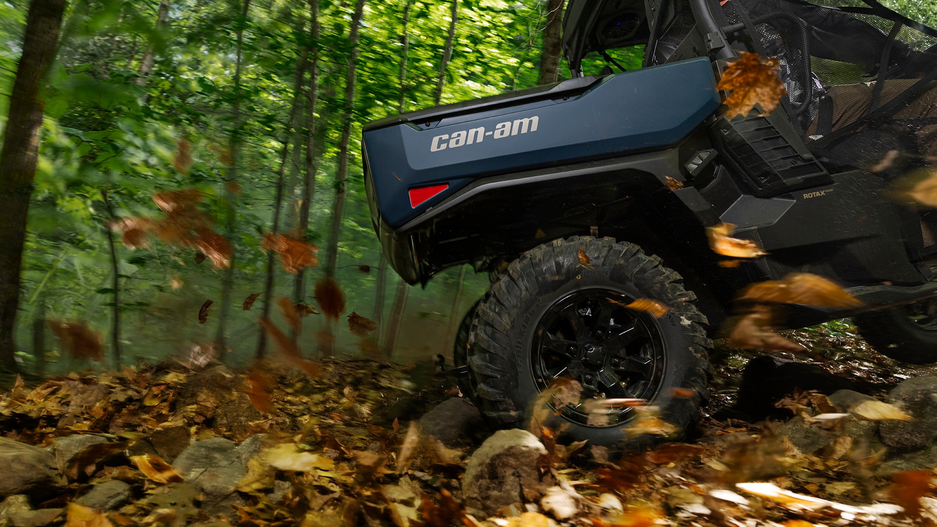 2026 Can-Am Defender SxS vehicle riding through a leafy forest