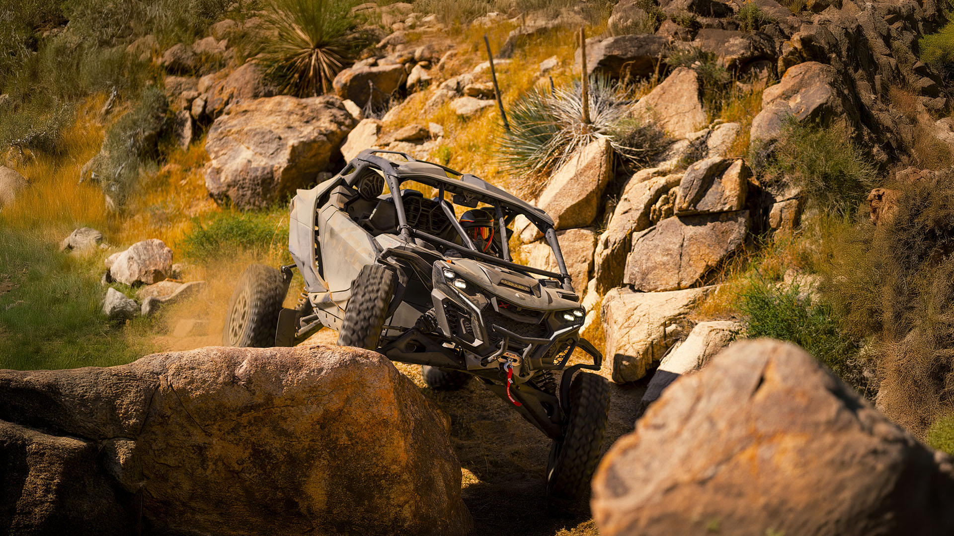 2026 Can-Am Maverick R X RC rolling across numerous rocks 