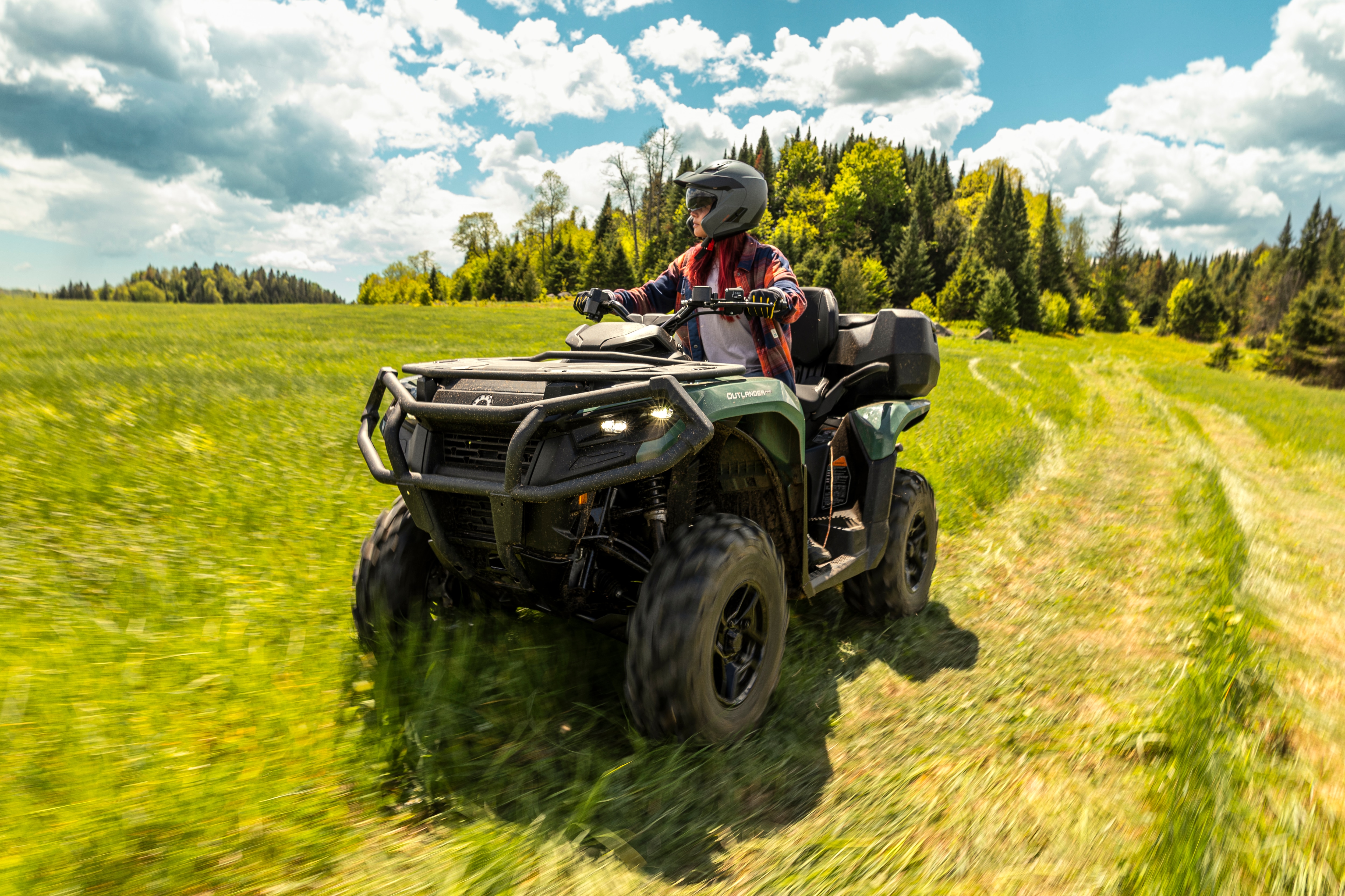 A Can-Am Outlander Pro ATV riding on the grass