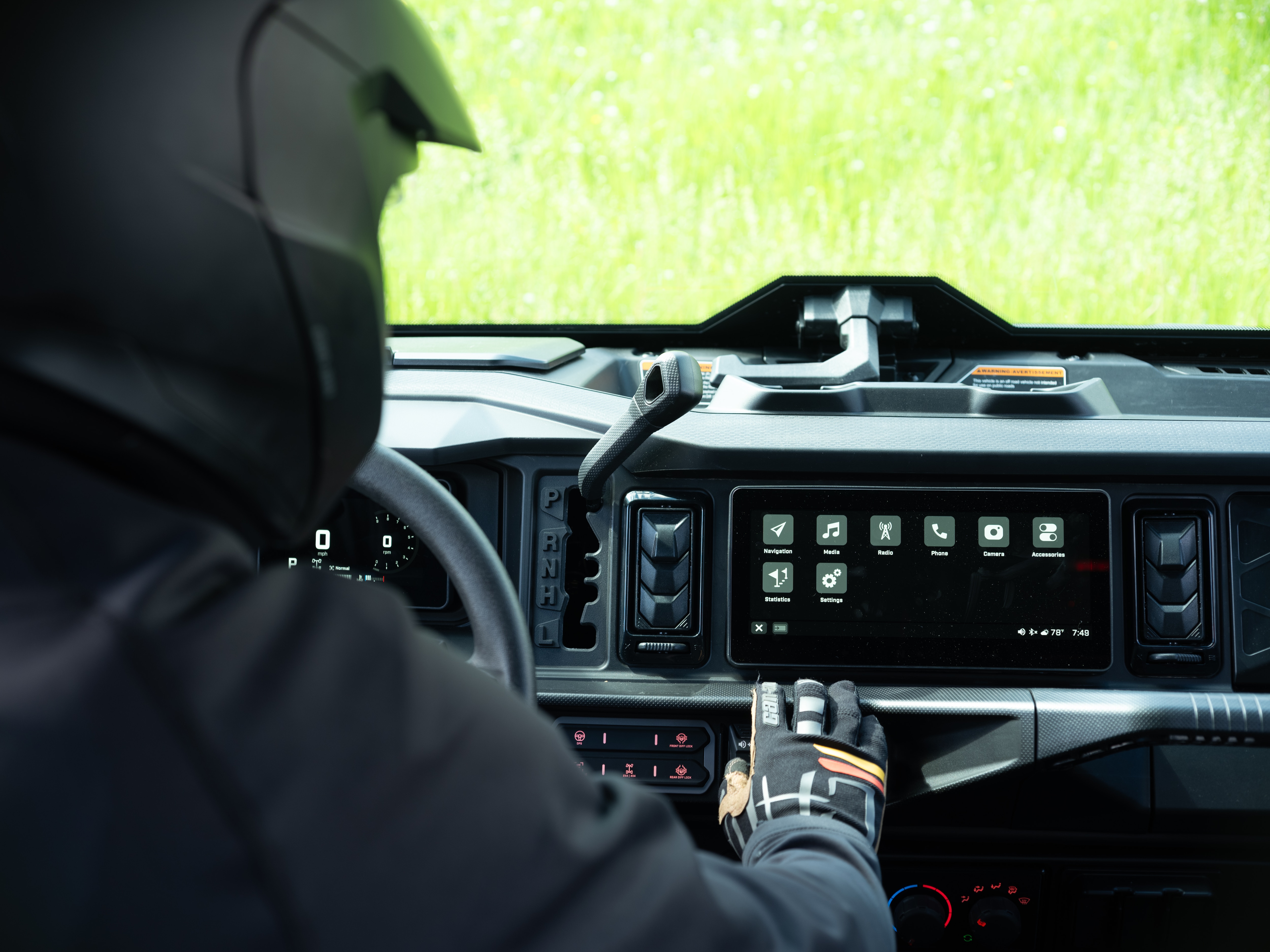 Un conducteur à l’intérieur de son côte à côte Can-Am utilisant ses écrans