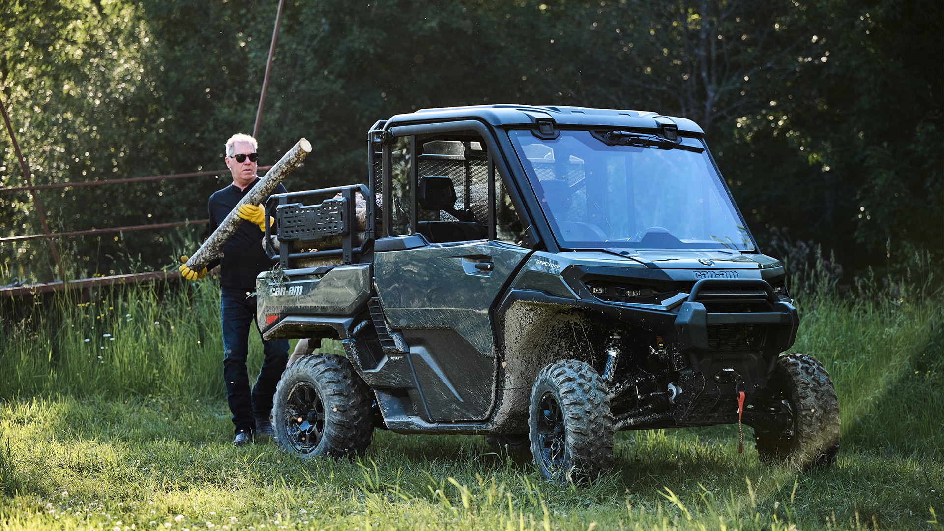 Un hombre cargando troncos en la parte trasera de su Can-Am Defender