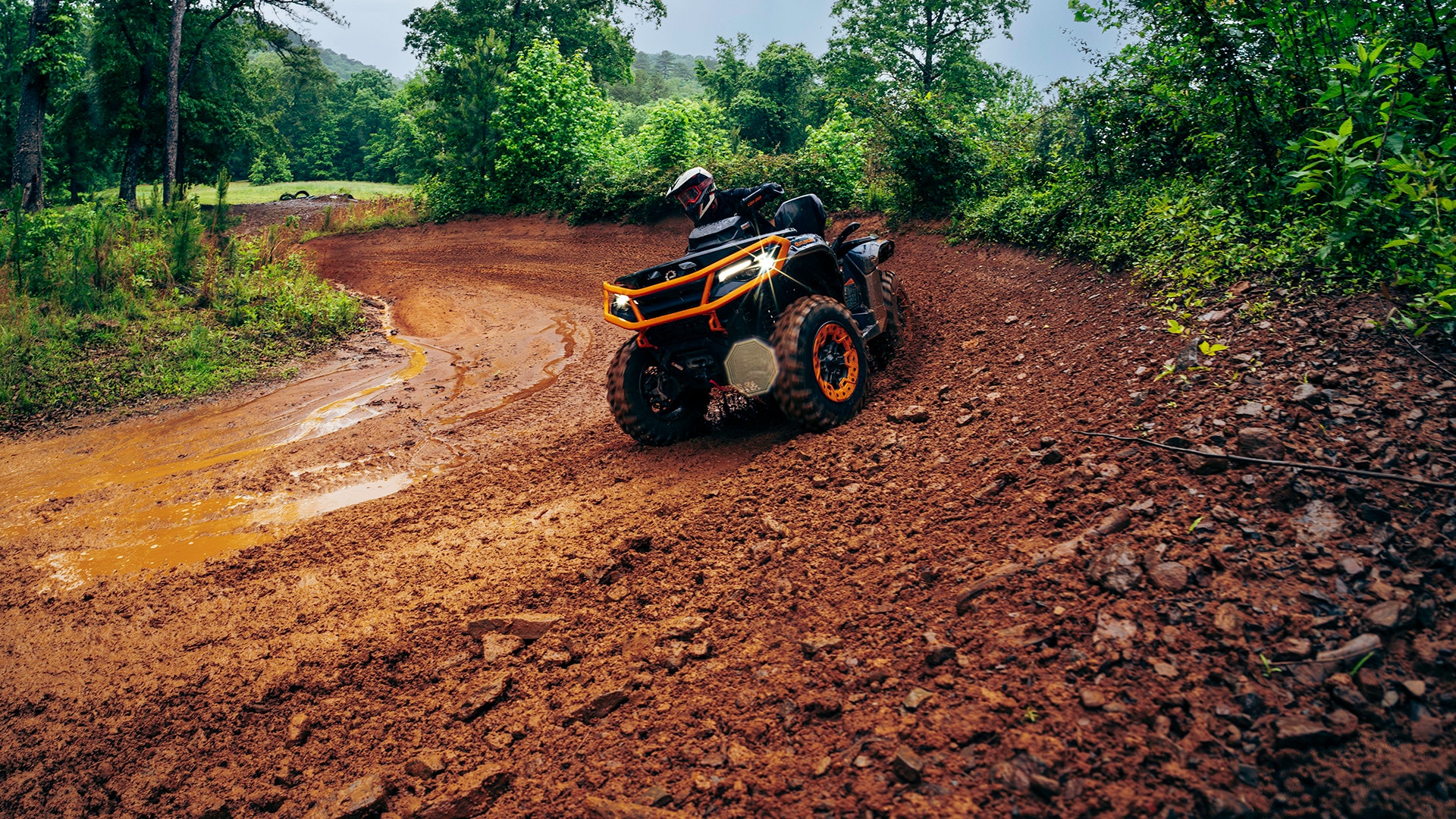 El nuevo ATV Can-Am Outlander 1000-1000R 2027 circulando por un sendero embarrado