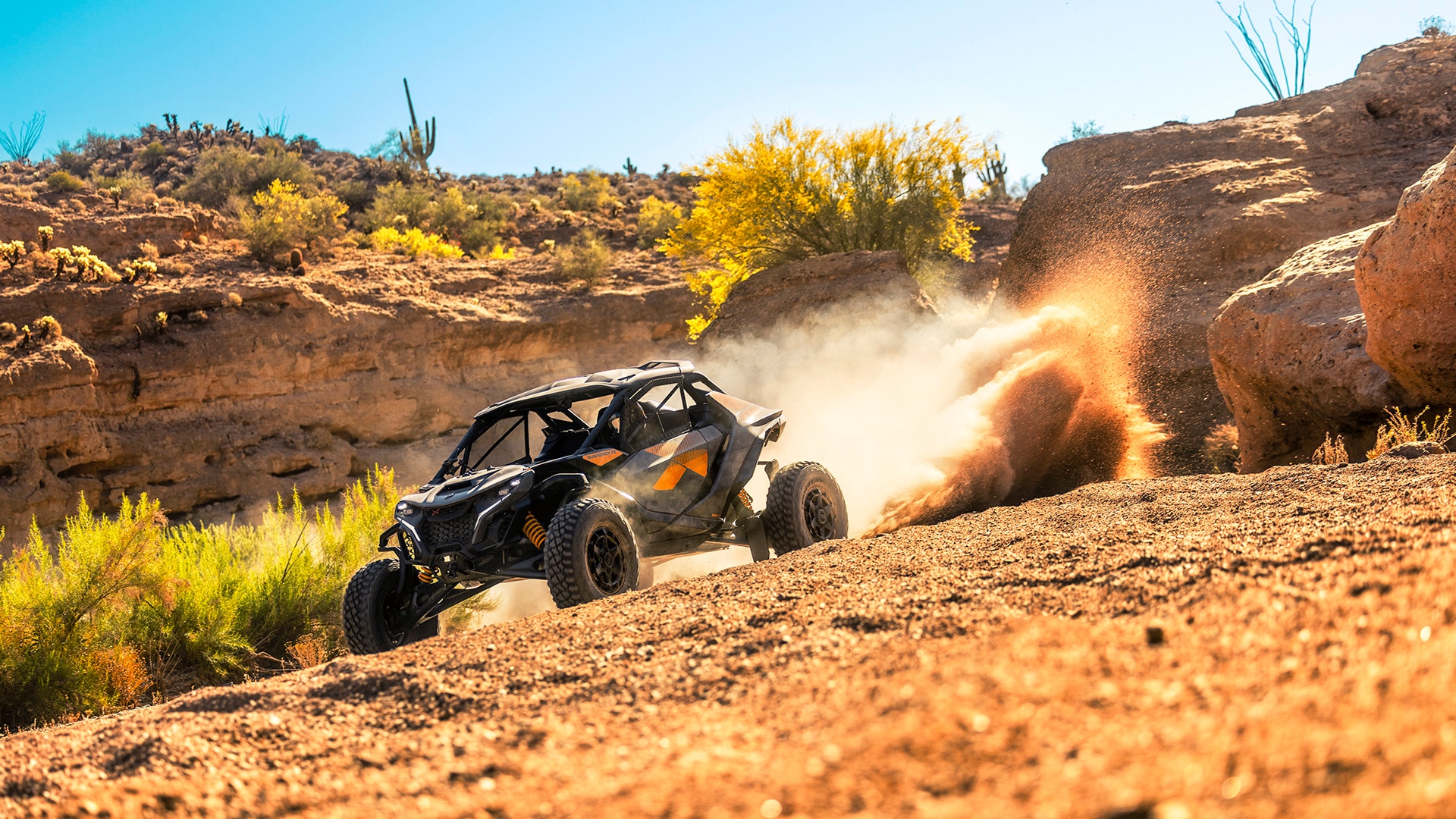 Un vehículo side-by-side Can-Am Maverick R 2027 circulando entre rocas, dejando una estela de polvo detrás de él