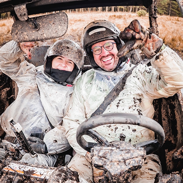 Duas pessoas sorrindo no interior da cabine de um veículo Can-Am. 
