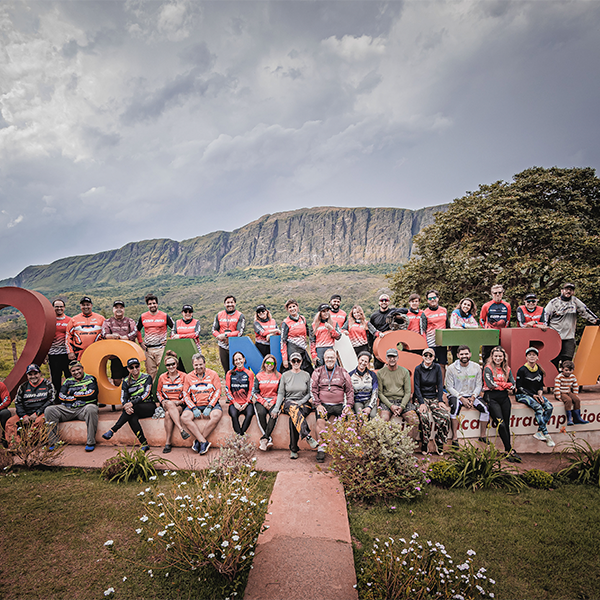 Um grupo de pessoas posando em frente a um letreiro colorido em uma área aberta. 