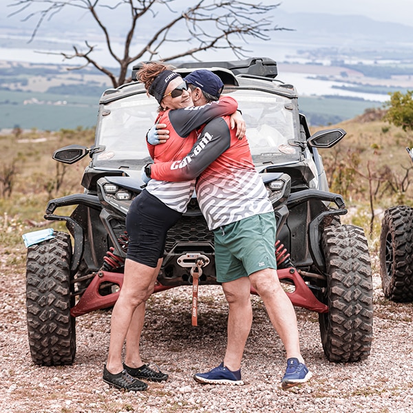 Um casal se abraçando na frente de um veículo Can-Am. 