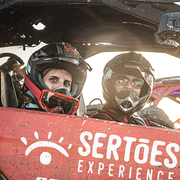 Piloto e passageiro dentro de veículo Can-Am com adesivagem oficial da Sertões Experience.