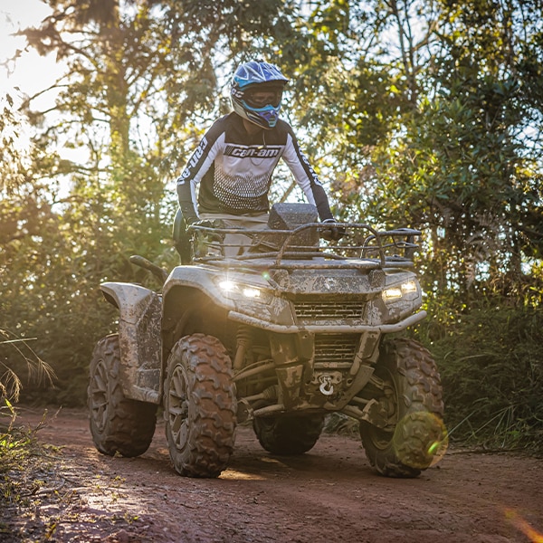 Um piloto conduzindo um quadriciclo Can-Am por uma estrada ou trilha de terra. 
