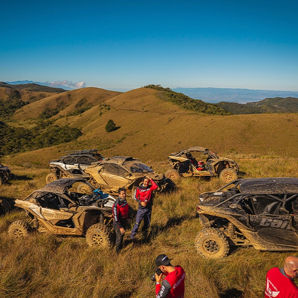 Uma vista aérea de um grupo de pessoas reunidas ao lado de vários veículos Can-Am estacionados.