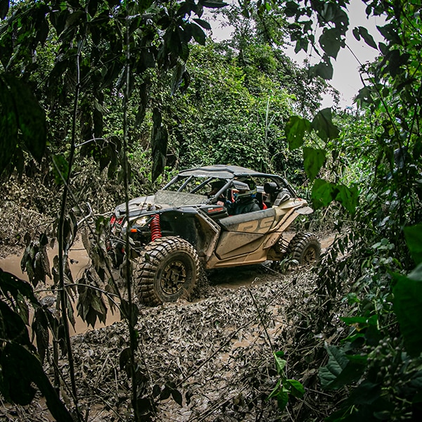 Veículo Can-Am de perfil estacionado em aclive de terra.