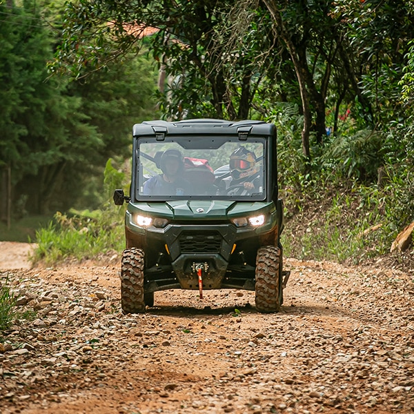 Veículo Can-Am utilitário descendo estrada de terra.