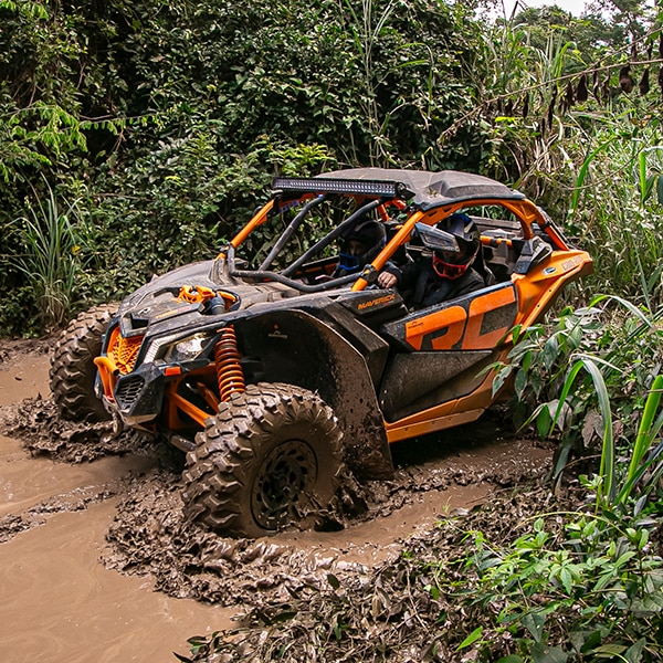 Veículo Can-Am em manobra off-road em trecho de lama.