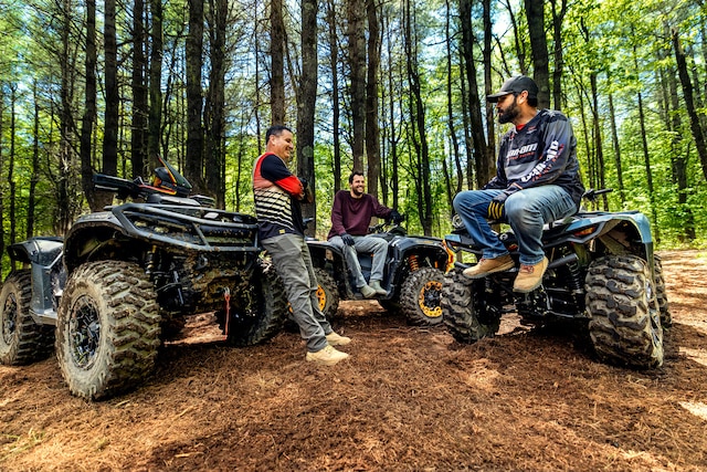 Três entusiastas de atividades ao ar livre fazendo uma pausa de pilotar seus ATVs Can-Am na floresta