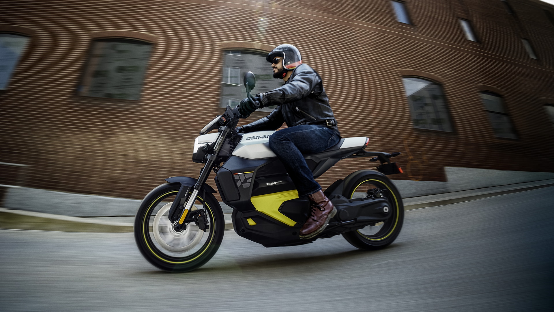 A motorcyclist riding a naked Can-Am Pulse electric motorcycle on a city street 