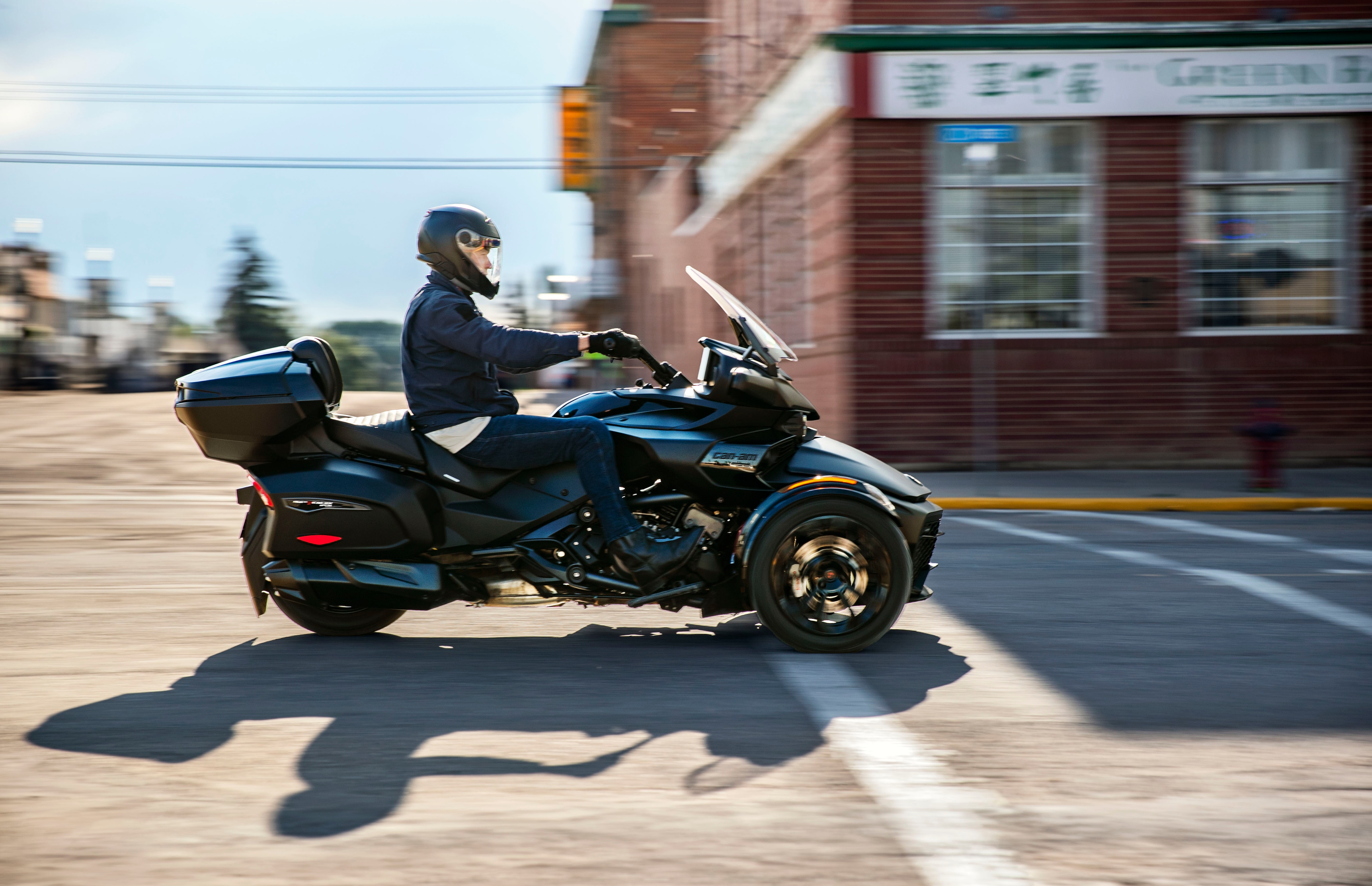 Pilote roulant à toute allure sur une route bordée d'arbres sur sa moto Can-Am à trois roues