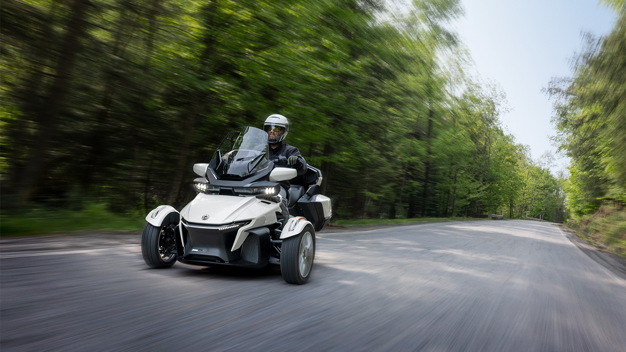 Couple riding a Can-Am Spyder RT near a field