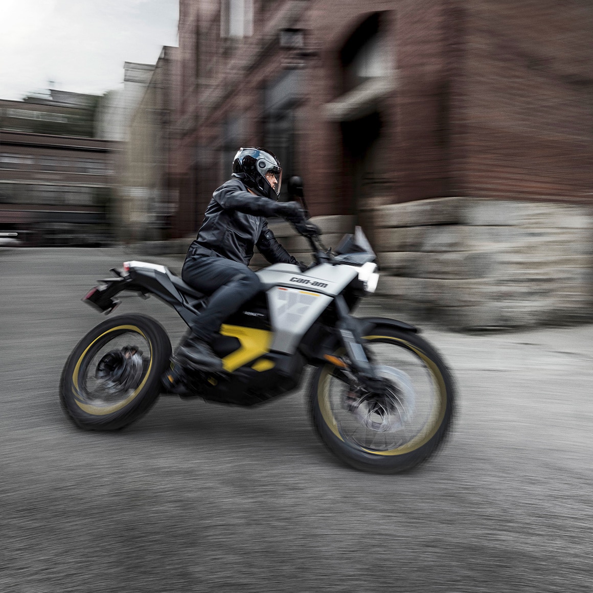 Un homme tournant le coin d’un bâtiment sur sa moto électrique Can-Am Origin 2027