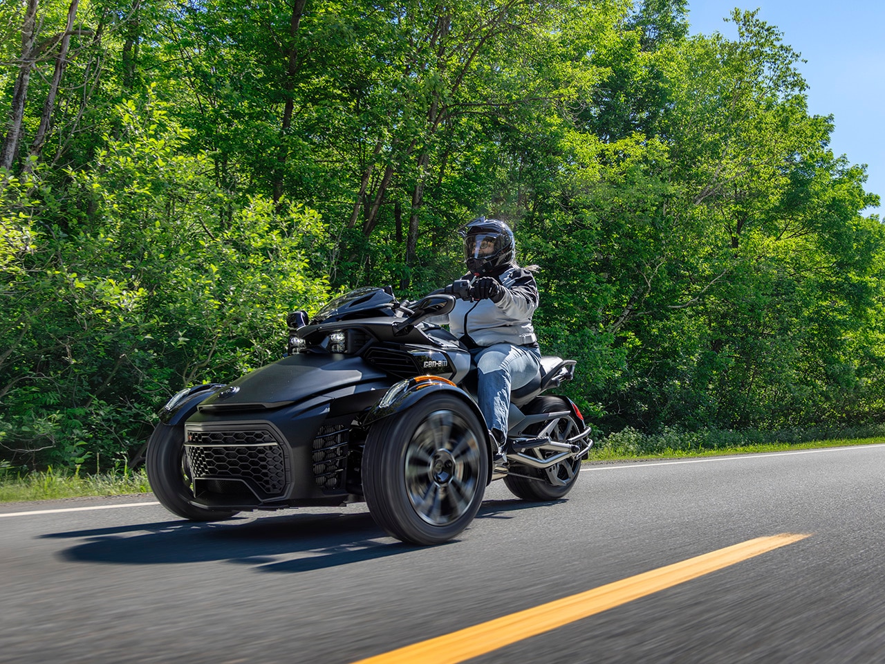 Une femme conduisant la nouvelle moto 3-roues Can-Am Spyder F3