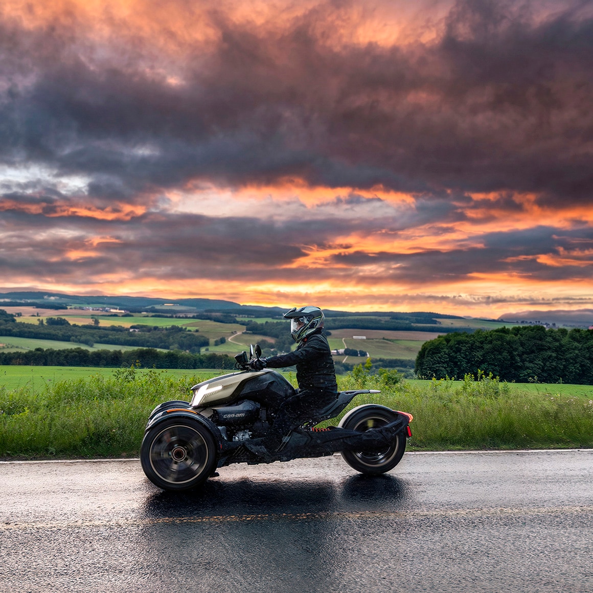 Le nouveau Can-Am Ryker 2027 roulant sur une route légèrement mouillée sous un ciel spectaculaire au coucher du soleil