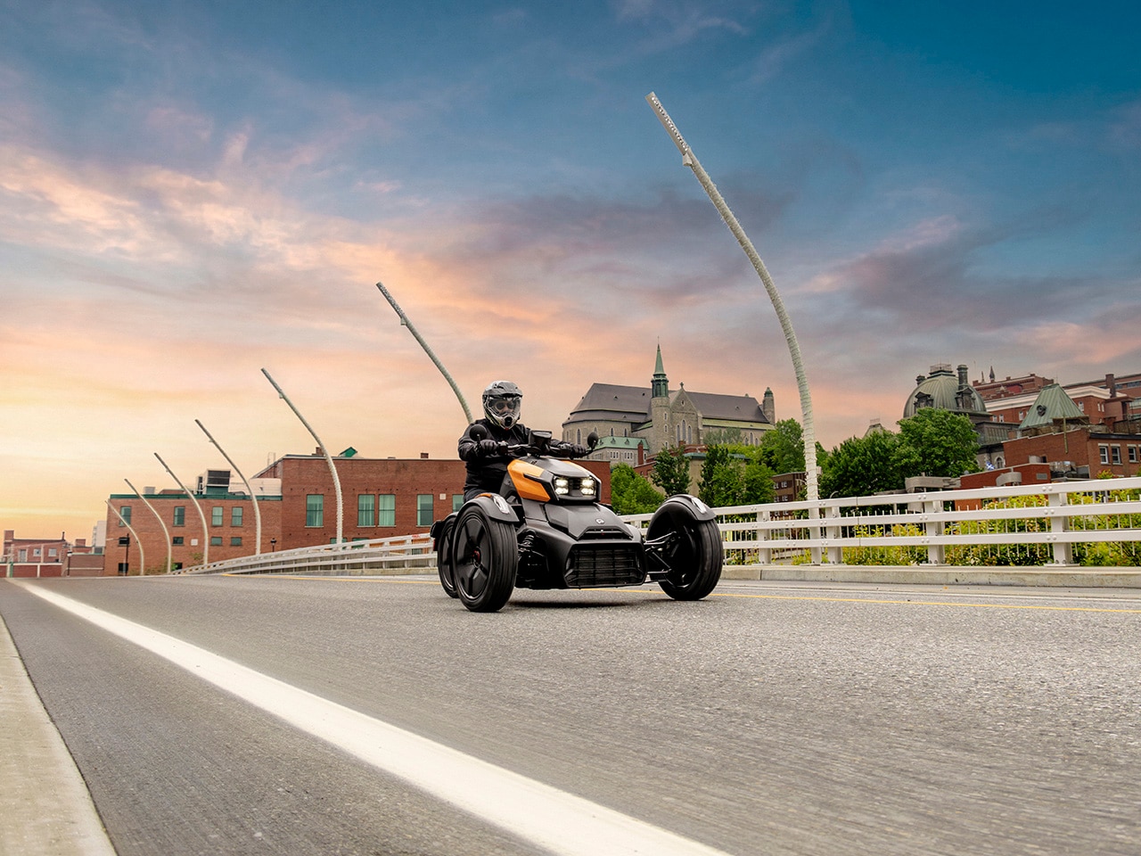 Un Can-Am Ryker 2027 roulant sur un pont avec une ville en arrière-plan
