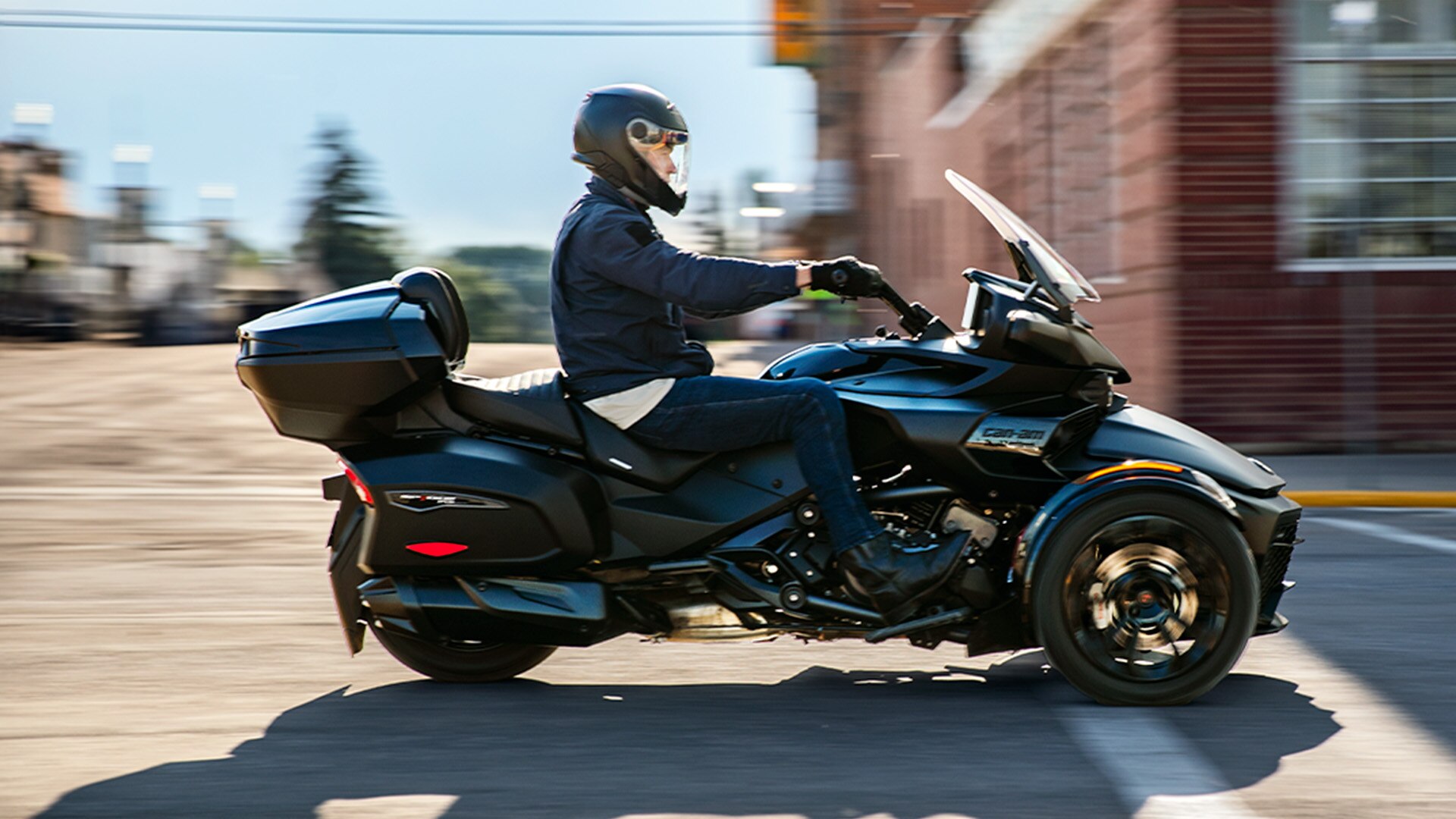 3-wheel Can-Am motorcycle equipped with a LinQ storage box riding through the city