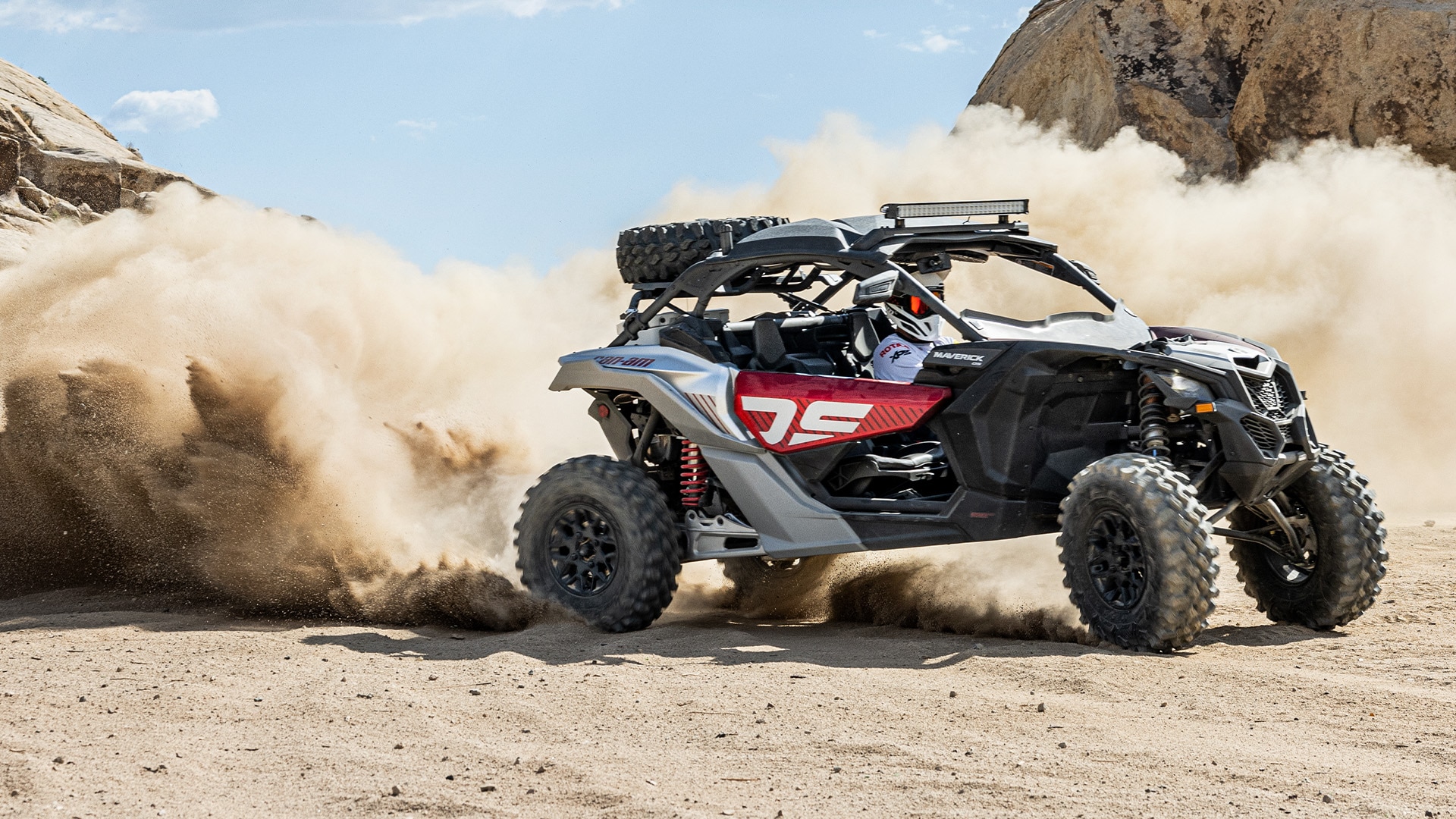 Rider in Can-Am Maverick X3 ripping around the desert and kicking up dust clouds 