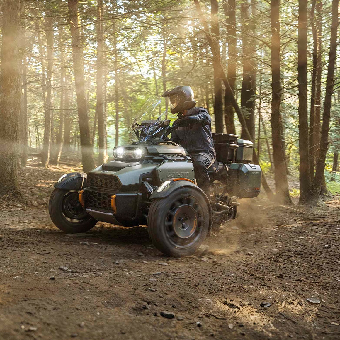 A Can-Am Canyon driving on a dirt road in the middle of the forest