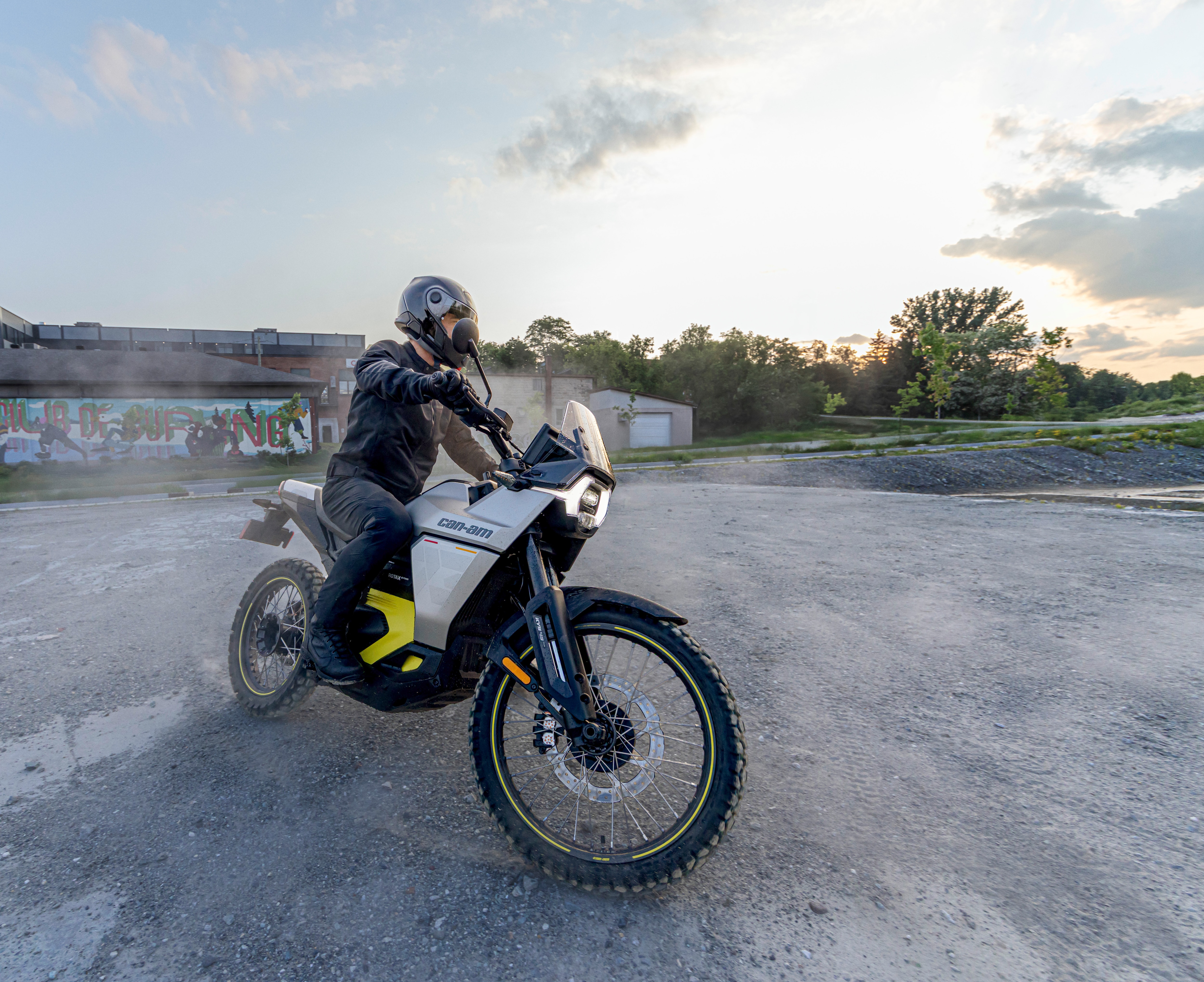 A Can-Am Origin electric motorcycle riding on a gravel parking lot