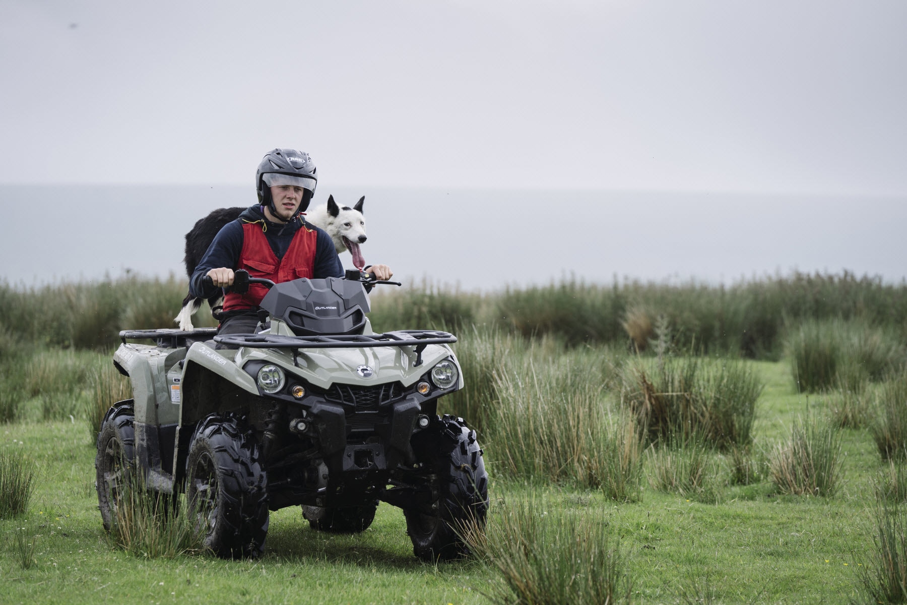 Can-Am Outlander on a field with owner and dog