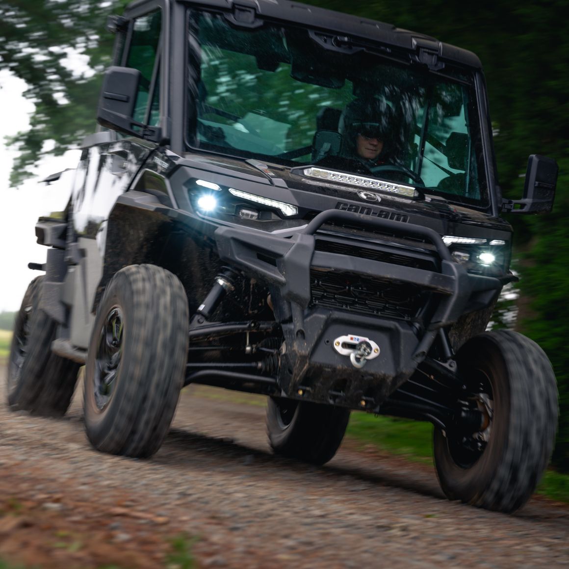 Mann fährt einen Can-Am Traxter XU HD11 auf einem Feldweg