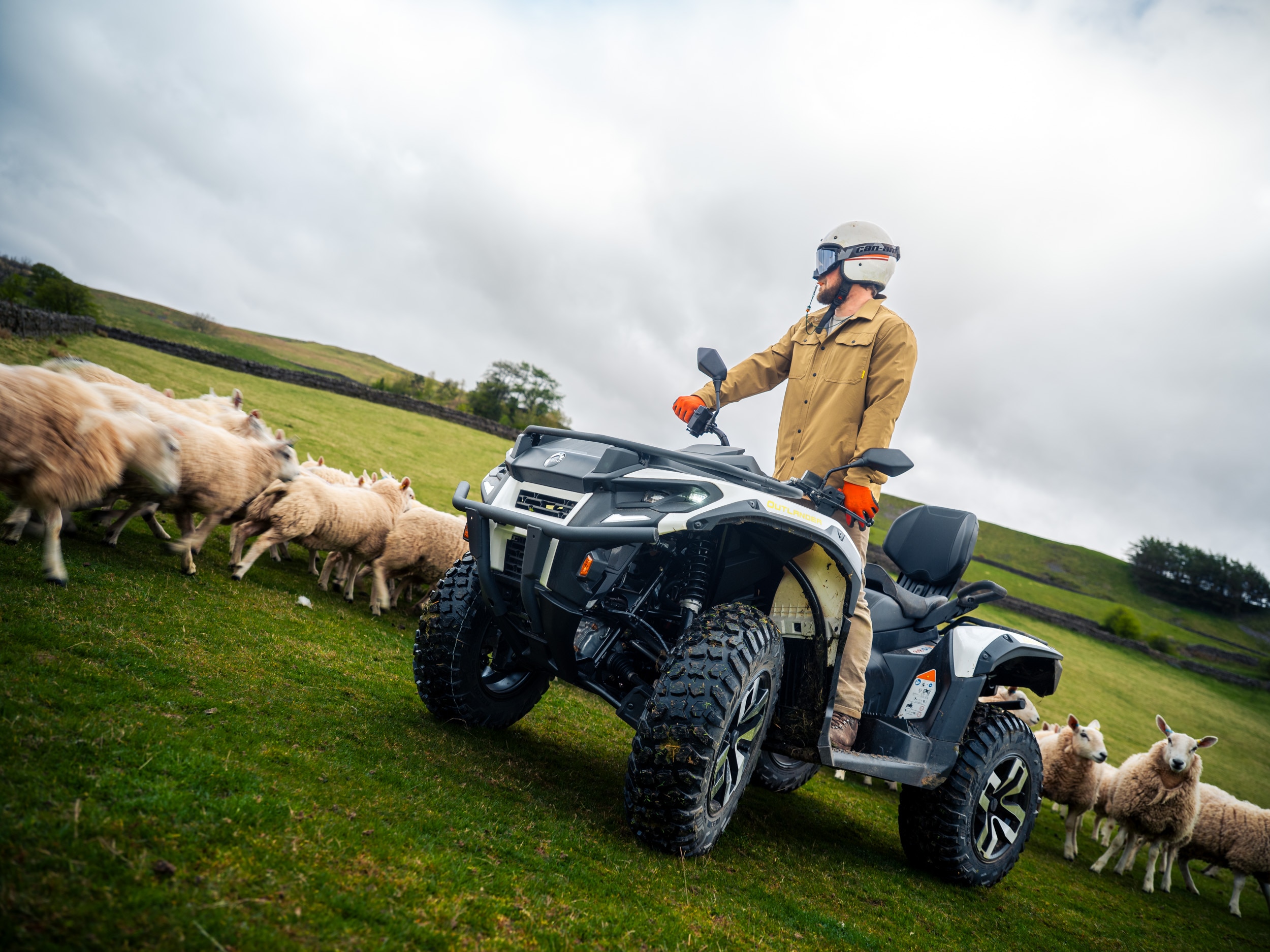 Un agriculteur debout sur un quad électrique Can-Am Outlander MAX à côté de moutons