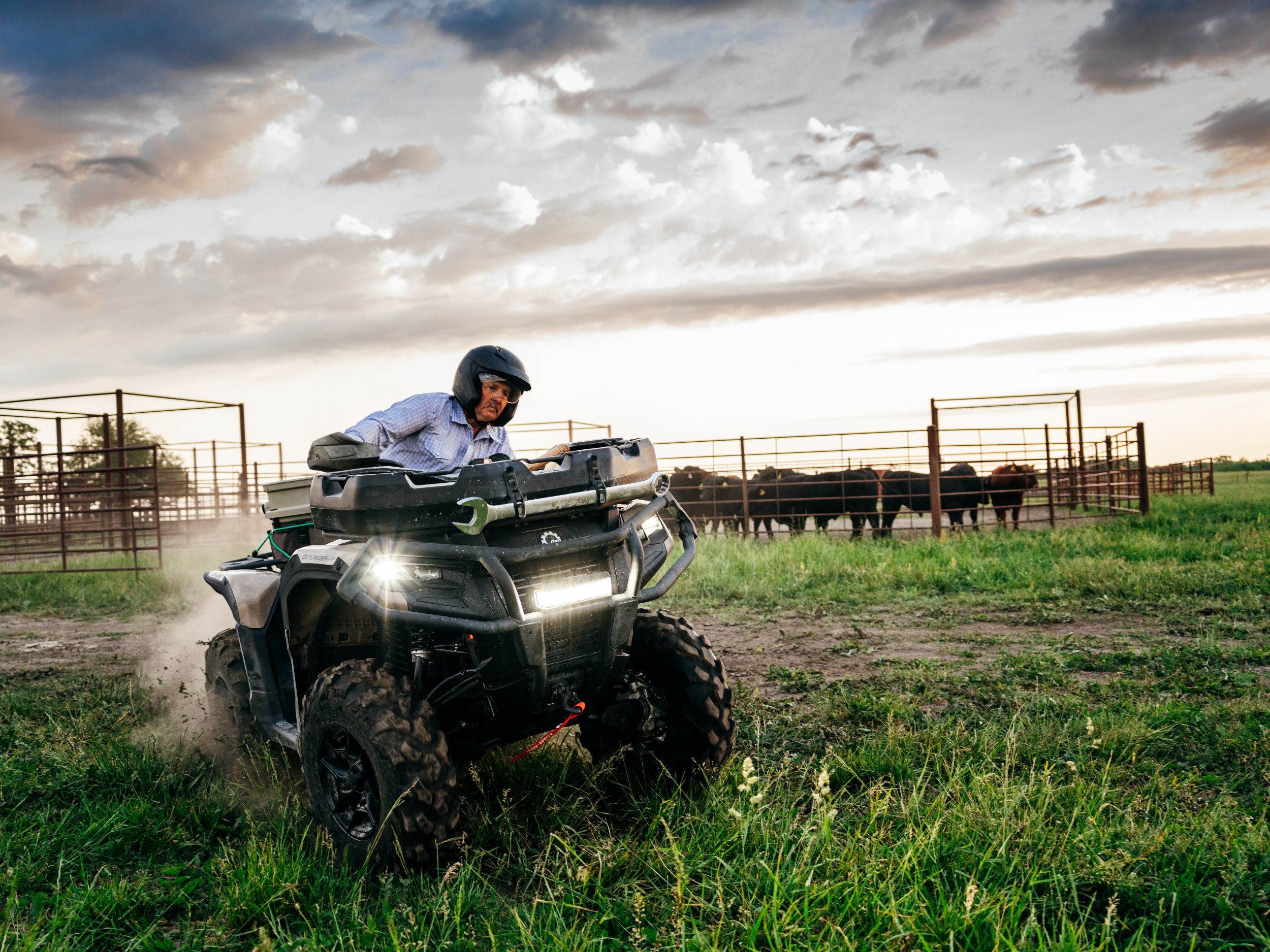 Boer rijdt op een Can-Am Outlander PRO quad in een veld naast een veekraal