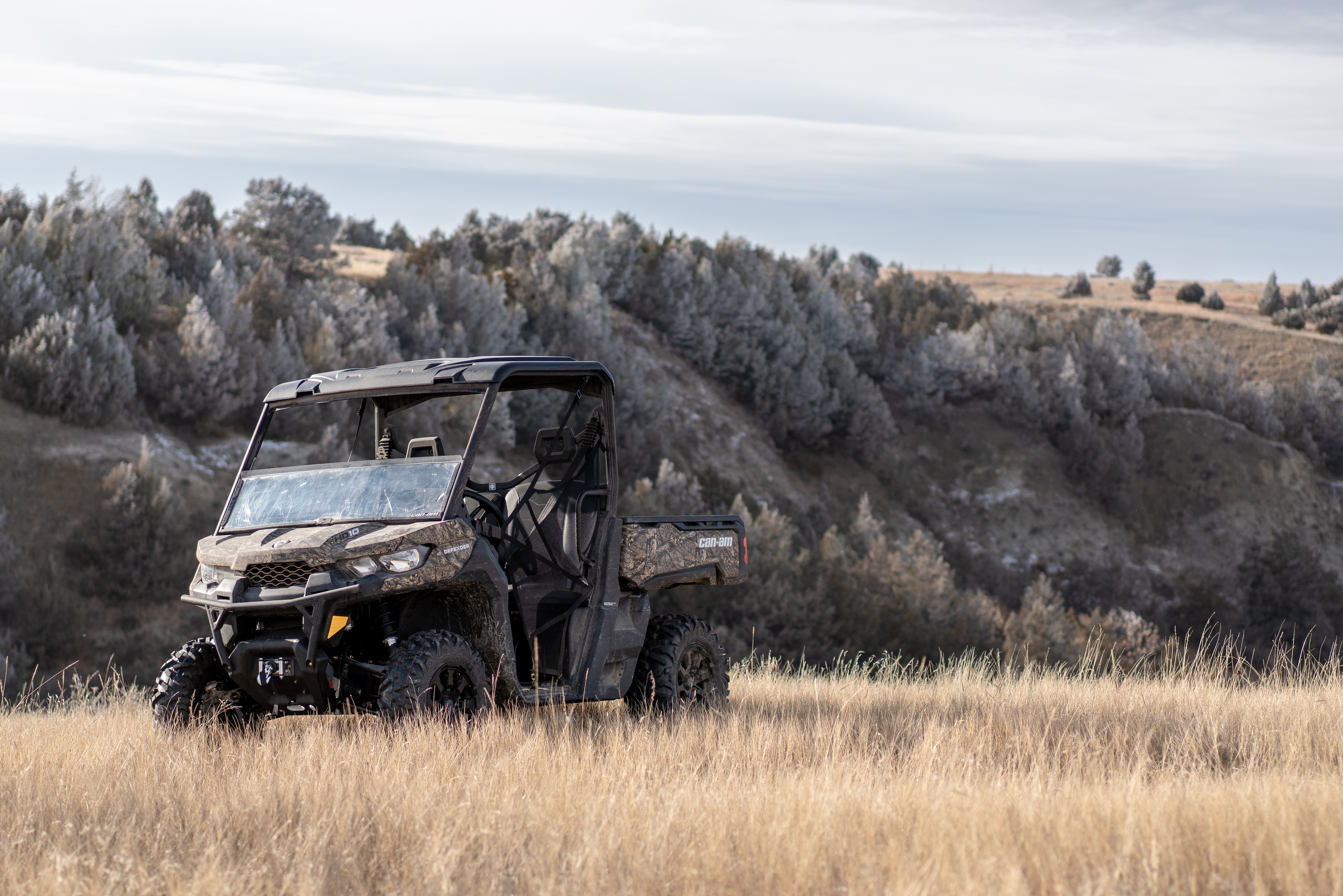 A parked Can-Am Defender side-by-side with Mossy Oak Camo in nature