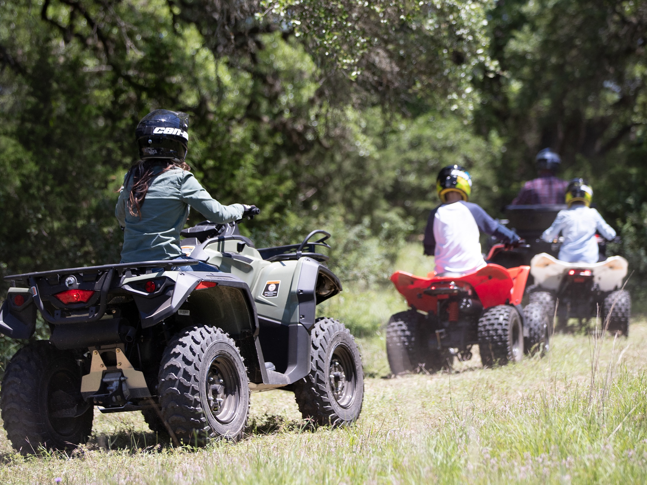 Young riders on their Can-Am DS watched by an adult 
